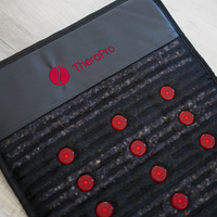 TheraPro massage mat with red buttons on a light wooden surface