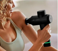 Woman using a massage gun on her arm with a blurred background