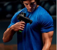 Person using a massage gun on their arm with a blurred background