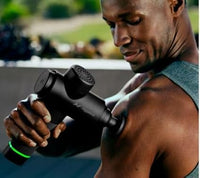 Man using a massage gun outdoors with blurred background
