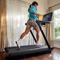 Person using a treadmill in a home setting with a window in the background