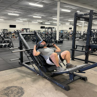 Man exercising on a leg press machine in a gym.