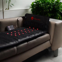 TheraPro massage mat on a beige couch with visible red lights