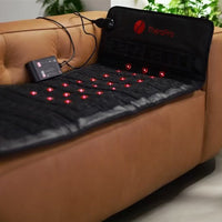 TheraPro heating pad on a brown leather couch with visible red lights.