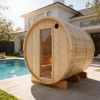 Wooden barrel-shaped sauna in a backyard with a pool and house in the background