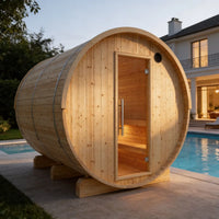 Wooden barrel-shaped sauna by a poolside with a house in the background