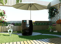 Black cylindrical planter with decorative elements in a garden setting