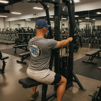 Man exercising on a gym machine in a well-equipped gym.