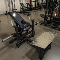 Gym weight bench with weight plates on a concrete floor in a gym setting